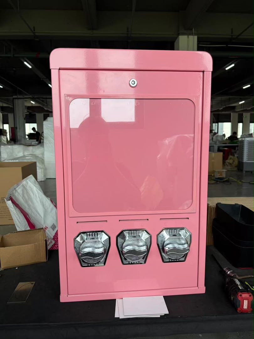 Pinker Postkartenautomat V3 mit drei Schächten auf einem Arbeitstisch in der Werkstatt